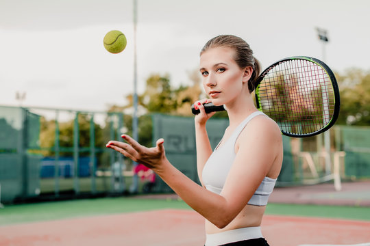 Young Tennis Player Woman Tossing Ball Up With Racket On Court