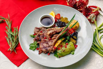 Grilled meat with vegetables and sauce on a white plate