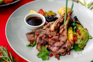 Grilled meat with vegetables and sauce on a white plate