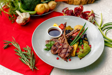Grilled meat with vegetables and sauce on a white plate