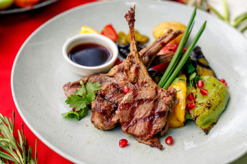 Grilled meat with vegetables and sauce on a white plate