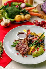 Grilled meat with vegetables and sauce on a white plate