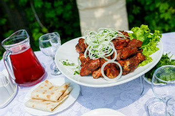 A beautiful portion of juicy kebabs of red meat lies in a plate on a served table on the street.