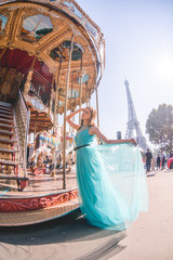 Beautiful young girl strolling through Paris next to the carousel, vintage atmosphere