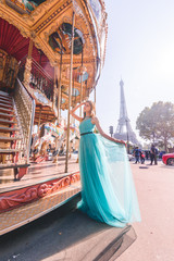 Naklejka premium Beautiful young girl strolling through Paris next to the carousel, vintage atmosphere