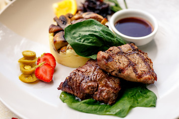 pieces of grilled meat with mushrooms and mashed potatoes