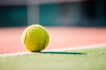 yellow tennis ball on clay court on sunny day