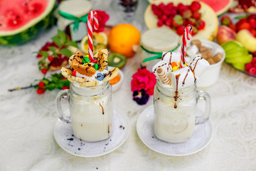 Crazy shake top with marshmallow, waffles, slices of banana and sweets on a bright colored background