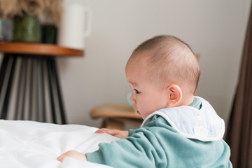 Asian baby in the room reaches for something