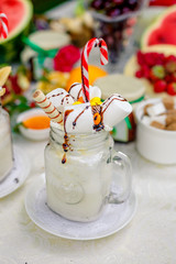 Crazy shake top with marshmallow, waffles, slices of banana and sweets on a bright colored background