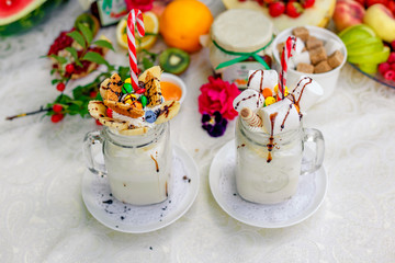 Crazy shake top with marshmallow, waffles, slices of banana and sweets on a bright colored background