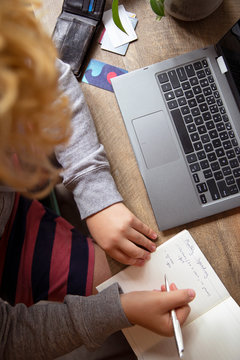 A teenager is calculating his monthly budget in a notebook at his desk