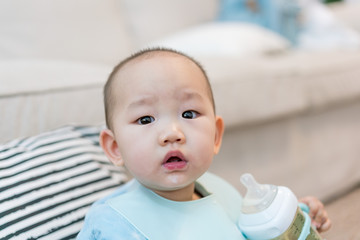 Baby in pajamas eating milk in the room