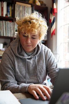 Blonde teenager studying at home using a laptop