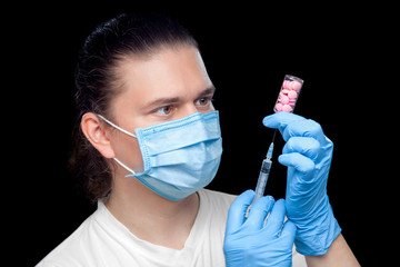 a virologist in a protective mask and sterile gloves with a syringe in his hands is collecting...