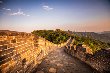 Golden sunlight blankets the Great Wall of China on a moody, cloudy, afternoon near Beijing, China.
