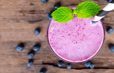 Blueberry smoothie purple colorful fruit juice milkshake blend beverage healthy high protein the taste yummy In glass drink episode morning on a wooden background from top view.
