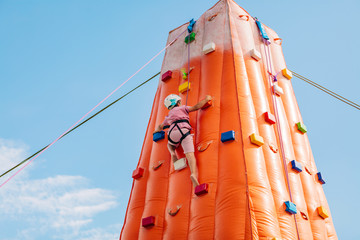 Boy practicing climbing on an inflatable climbing wall. Is behind