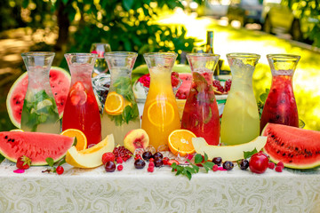 fresh lemonade collection (watermelon, orange, lemon, strawberry and berry) in the street, on a wooden table with fruit