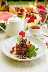 chocolate sponge cake with ice cream and fruit on a served table