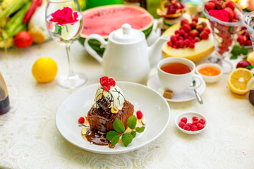 chocolate sponge cake with ice cream and fruit on a served table
