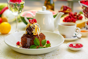 chocolate sponge cake with ice cream and fruit on a served table