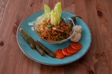 
pickles, peppers, bulgur, lettuce, carrots in a blue plate