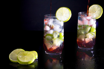 Campari with silver rum with ice and lemon on black background