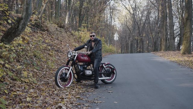Portrait of stylish biker behind a motorcycle nodding head