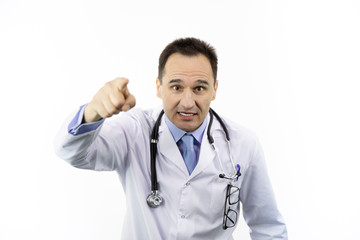Middle-aged angry doctor in white coat and stethoscope annoyed and frustrated shouting with raised hand pointing finger to you, isolated white background, medical warning, threat concept