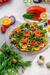 fresh salad with vegetables, greens and red fish with caviar served on the table, healthy food