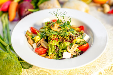 Fresh salad with mushrooms, cheese, tomatoes, herbs and vegetables served on the table with the ingredients, healthy food