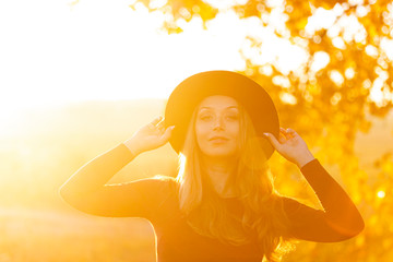 Beautiful caucasian woman with long hair holding her hat with hands outside on warm sunny day....