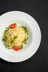 Tasty appetizing classic italian spaghetti pasta with tomato sauce, cheese parmesan and basil on plate on dark table