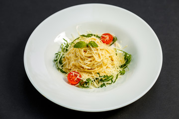 Tasty appetizing classic italian spaghetti pasta with tomato sauce, cheese parmesan and basil on plate on dark table