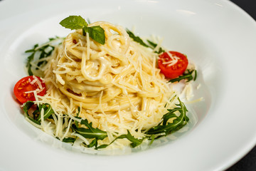 Tasty appetizing classic italian spaghetti pasta with tomato sauce, cheese parmesan and basil on plate on dark table