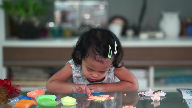 Cute little girl playing with play doh indoor.