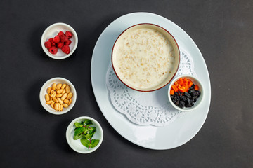 rice porridge with milk, healthy breakfast with raisins, nuts, mint on a white plate