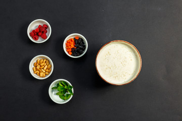 rice porridge with milk, healthy breakfast with raisins, nuts, mint on a white plate