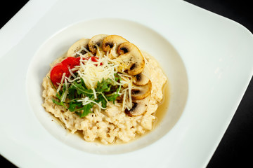 rice porridge with mushrooms, parmesan cheese, arugula and tomatoes