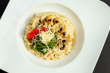 rice porridge with mushrooms, parmesan cheese, arugula and tomatoes