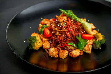 Thai cuisine, rice noodles with chicken, broccoli, tomatoes and greens