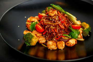 Thai cuisine, rice noodles with chicken, broccoli, tomatoes and greens