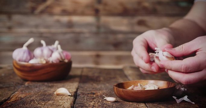 Men hands peel garlic from skin.