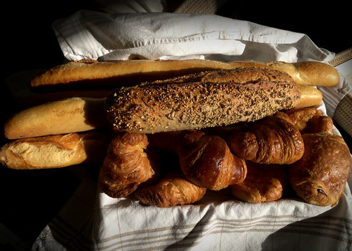 Fresh bread from a local market delivered in the morning in the South fo France with begets, seed covered dark bread and croissants in a linen lined basket.  