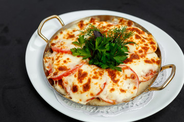 casserole with meat cheese, tomato and potatoes with greens