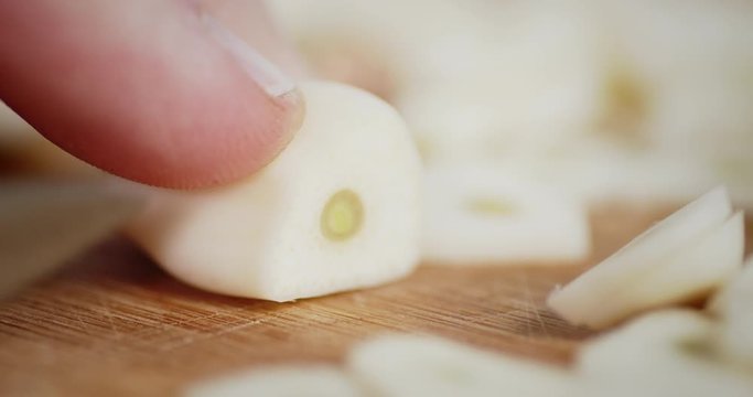 A knife cut the garlic into small pieces on a wooden table.