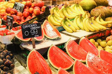 Watermelons strawberries bananas on a Barcelona market counter with price tag