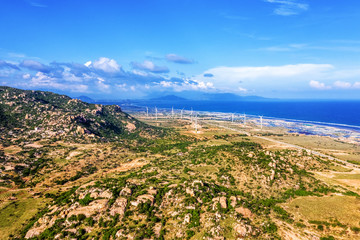 Aerial view of  wind turbines beside sea and coastal road Cam Ranh - Mui Dinh - Ca Na on a sunny day, Phuoc Dinh, Phan Rang, Ninh Thuan, Vietnam. Mui Dinh lighthouse 3 km away from here