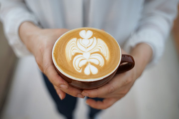 Latte art Coffee on hands at cafe